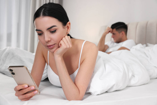 Internet addiction. Woman with smartphone ignoring her boyfriend in bedroom - Zdjęcie, obraz