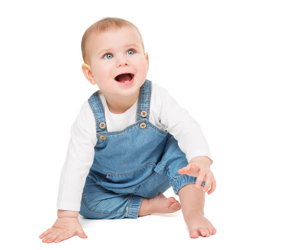 Happy smiling Baby in Jeans sitting over White isolated Background. Laughing little Child crawling looking up. Cheerful One Year Beauty Kid active playing - Fotoğraf, Görsel