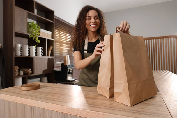 Worker with paper bags at counter in cafe, focus on hands - Photo, image