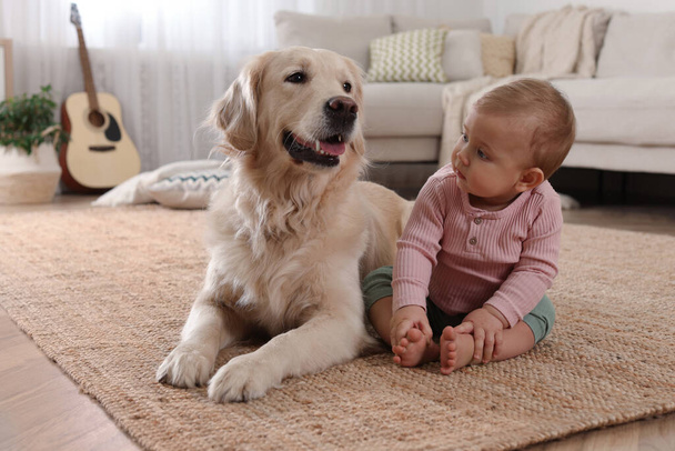 Cute little baby with adorable dog on floor at home - Photo, Image