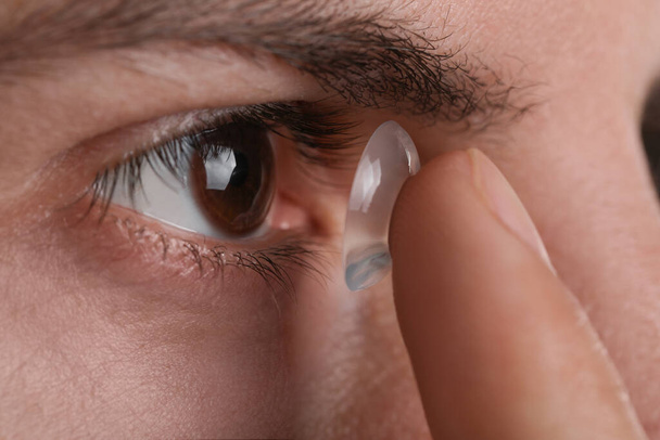 Closeup view of man putting contact lens in his eye - Foto, Imagen