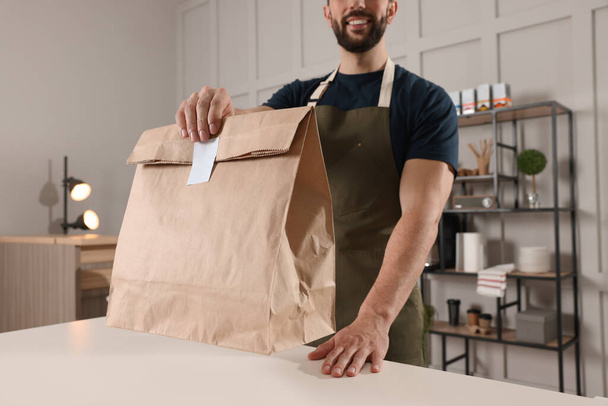 Worker with paper bag at counter in cafe, closeup - Foto, imagen