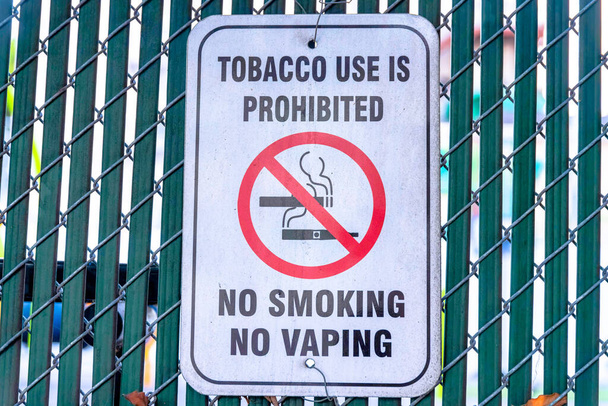Palenie tytoniu jest zabronione w San Francisco w Kalifornii. Zbliżenie znaku zakazu palenia na metalowym płocie siatkowym z listwami prywatności. - Zdjęcie, obraz