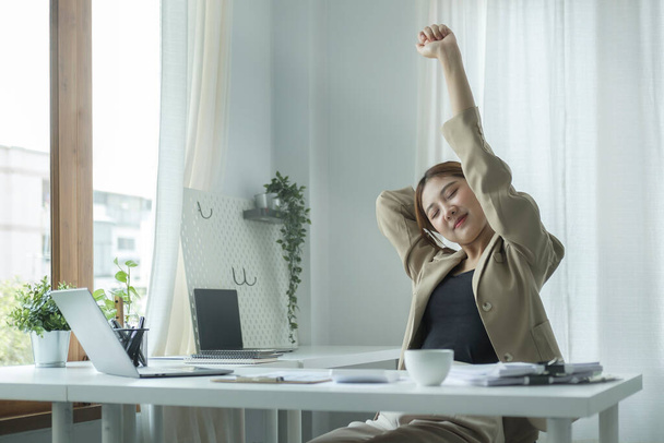 Calm businesswoman stretching her arms in the air, relaxing at workplace. - Foto, Imagem