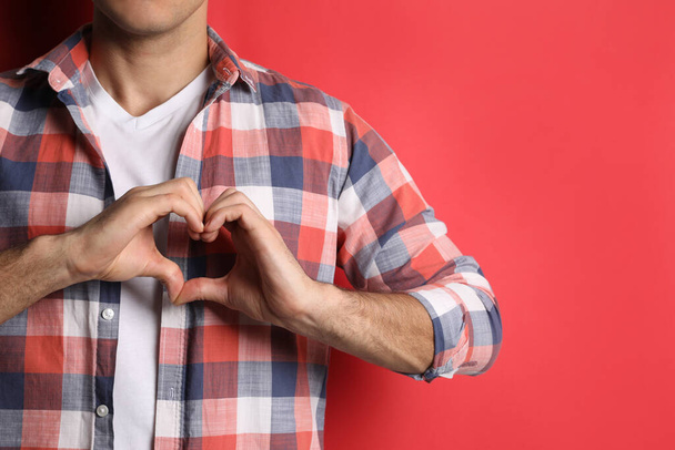 Man making heart with hands on red background, closeup. Space for text - Foto, Imagen