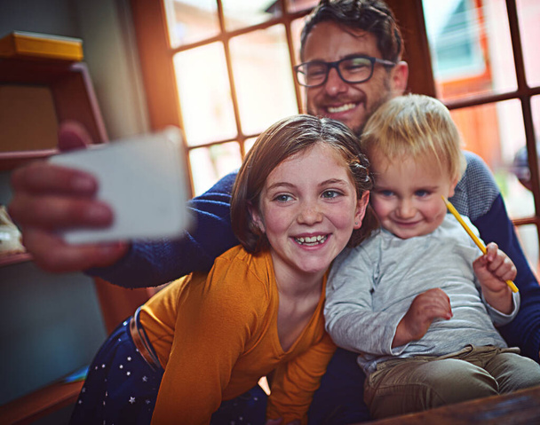 Che carino. Girato di un padre che si fa un selfie con suo figlio e sua figlia a casa. - Foto, immagini