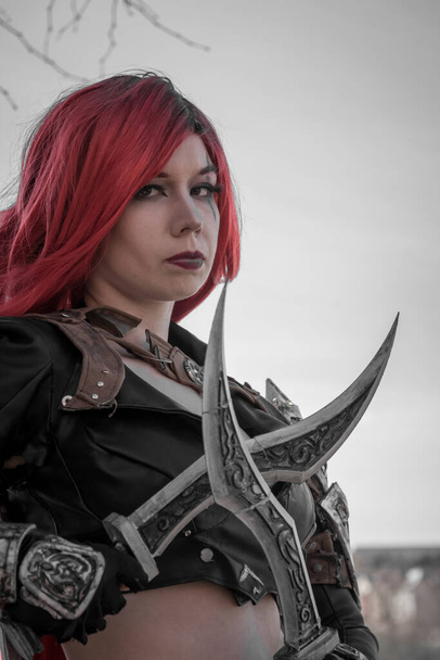 a woman with red hairs as a warrior with daggers in her hand - Foto, Imagen