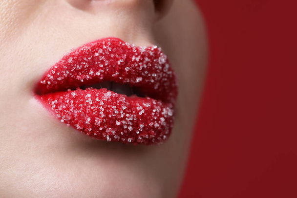 Young woman with beautiful lips covered in sugar on red background, closeup - Foto, Imagem