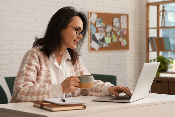 Жінка з сучасним ноутбуком і чашкою чаю вчиться вдома
 - Фото, зображення