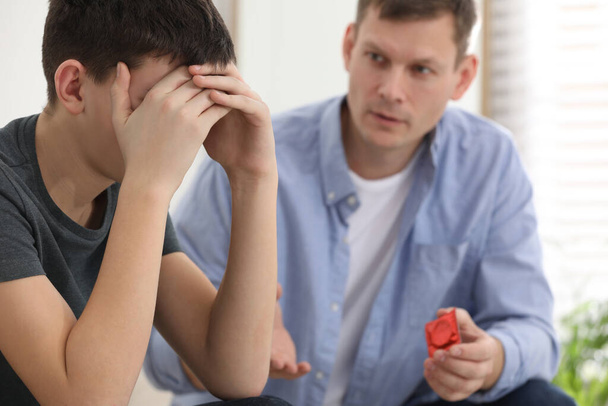 Father talking with his teenage son about contraception at home. Sex education concept - 写真・画像