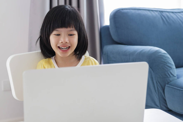 маленька азіатська дівчинка студент вчить онлайн за допомогою ноутбука вдома
 - Фото, зображення