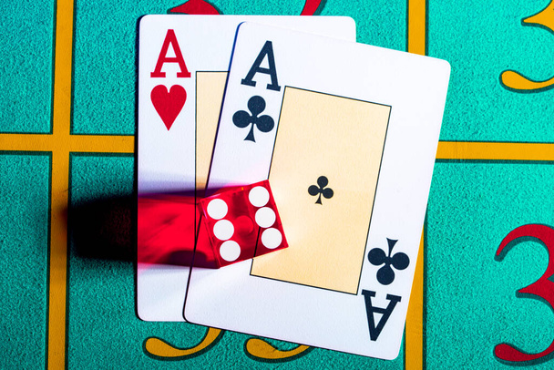 A pair of aces and red dice with the number six lying on a blue gaming table in a casino. Game cards and poker dice close up. Concept of casino games, gambling, poker, blackjack. - Zdjęcie, obraz