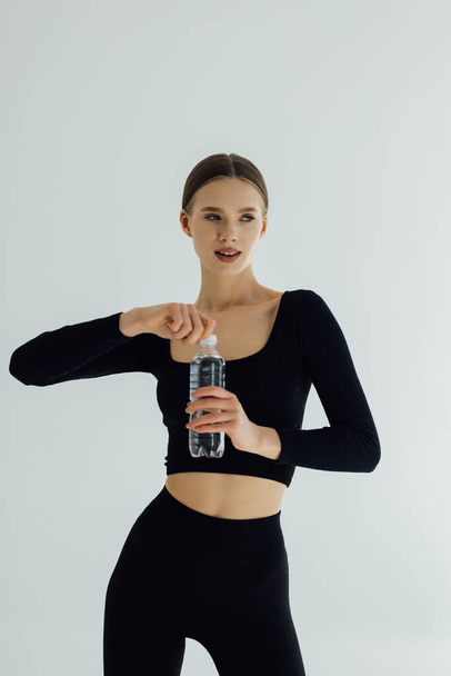 Mulher em sportswear água potável, isolado em branco
 - Foto, Imagem