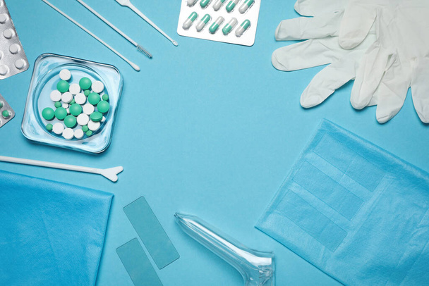 Frame of disposable gynecological examination kit and pills on light blue background, flat lay. Space for text - 写真・画像