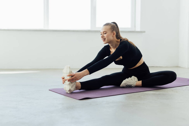Fit woman stretching her leg to warm up over white background - Valokuva, kuva