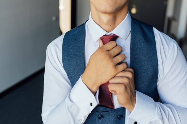 Young businessman in a blue suit adjusting his red tie - Fotoğraf, Görsel