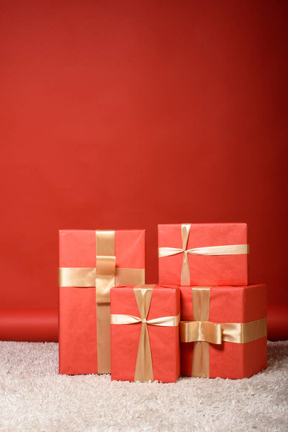 four boxes on a red background tied with shiny ribbons free space for an inscription - Foto, imagen