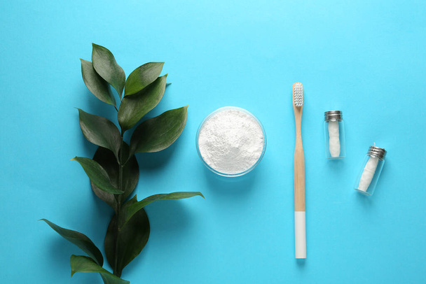 Bowl of tooth powder, brush, dental flosses and plant on turquoise background, flat lay. Space for text - Fotoğraf, Görsel