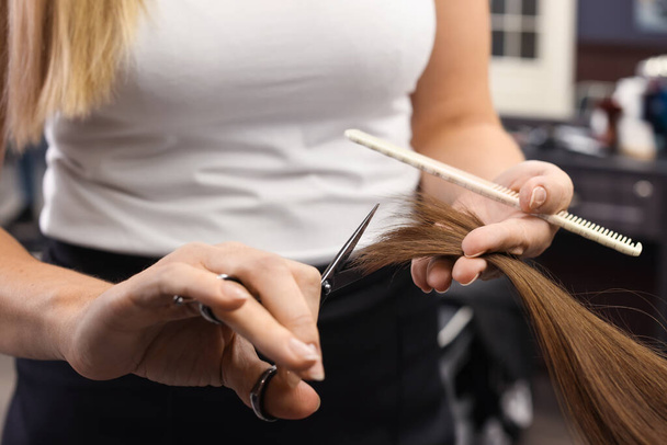 Professional hairdresser cutting woman's hair in salon, closeup - Foto, Imagen
