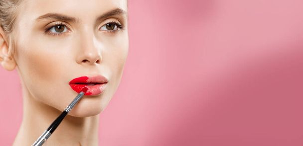 Ομορφιά έννοια - ευτυχισμένος καυκάσιος γυναίκα με μακριά μαλλιά και κόκκινα χείλη ποζάρει πάνω από ροζ φόντο στούντιο. - Φωτογραφία, εικόνα