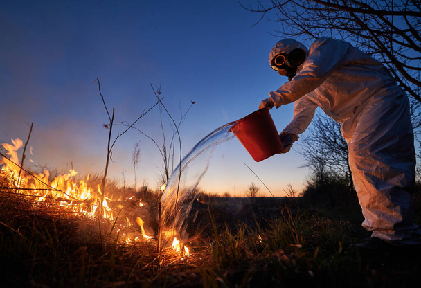 Πυροσβέστης οικολόγος σβήνουν φωτιά στο πεδίο το βράδυ - Φωτογραφία, εικόνα