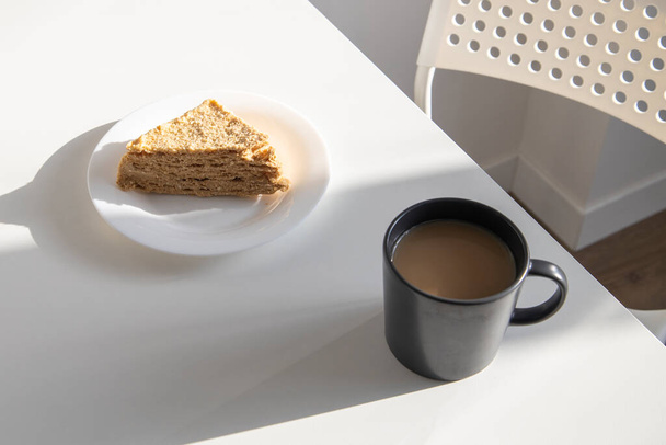 A cup of coffee and a piece of cake on a plate on the table. - Photo, Image