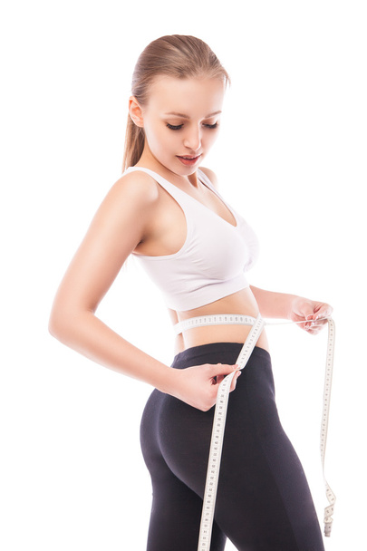 Slimming woman measuring thigh with tape - Fotó, kép