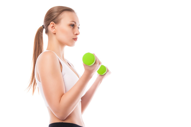 Athletic woman pumping up muscles with dumbbells - Foto, imagen