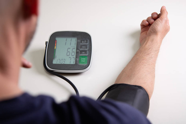 Middle aged man testing his blood pressure at home with a digital blood pressure monitor - Foto, Imagen