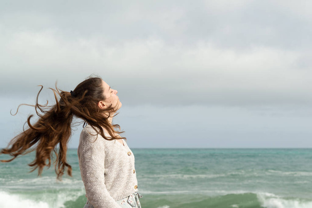 Mujer joven moviendo su larga cola de caballo con la brisa del mar. Concepto inspirador. - Foto, Imagen