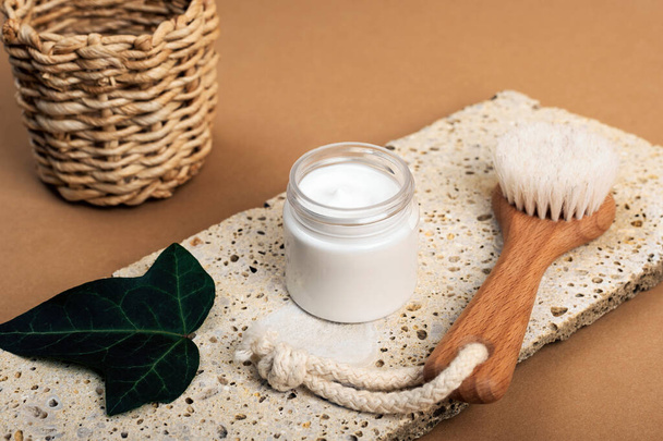 Cosmetic cream in a jar and face brush on natural stone. Spa and wellness, zero waste concept. - 写真・画像
