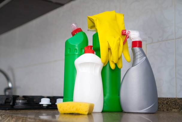 クリーニング製品、黄色のゴム手袋、ガスストーブの近くのキッチンテーブルのスポンジのクローズアップ。掃除、家事の概念 - 写真・画像