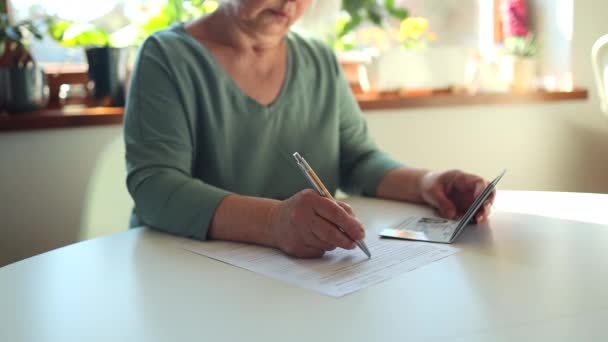 50 60s Kavkazská žena rukou psát perem v dokumentu PESEL na bílém stole na ministerstvu státní služby - Záběry, video