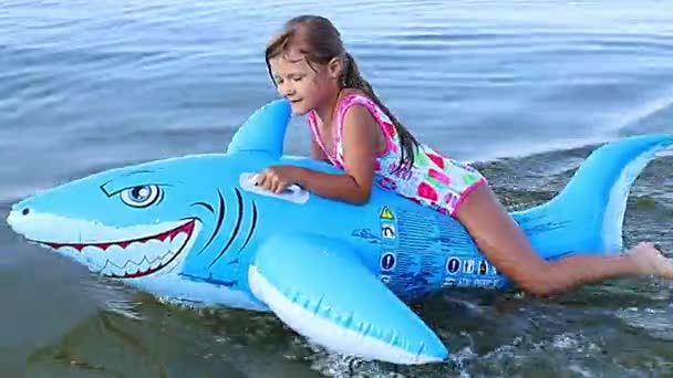  Menina feliz nadando em um brinquedo inflável do tubarão no mar - Filmagem, Vídeo