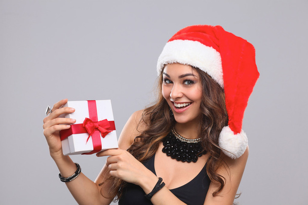 Woman in Santa hat holding gifts, isolated on gray background - Foto, imagen