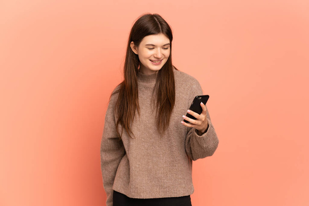 Giovane ragazza ucraina isolata su sfondo rosa invio di un messaggio o e-mail con il cellulare - Foto, immagini