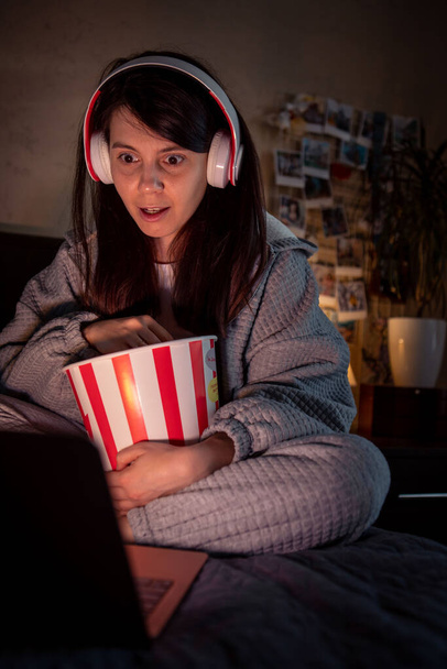 femme regarder film effrayant à la maison manger pop maïs casque - Photo, image