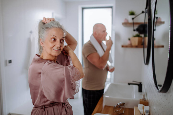 Senior couple in bathroom, brushing teeth and washing, morning routine concept. - Photo, image