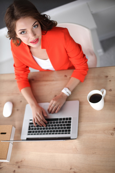 Attractive woman sitting at desk in office, working with laptop computer - Foto, Imagen
