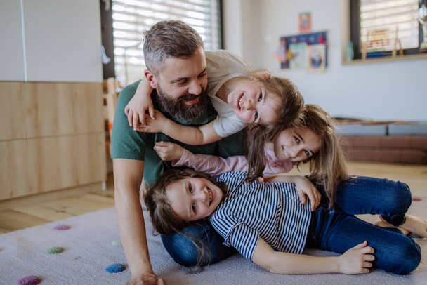 Cheerful father with three little daughters playing together at home. - Photo, Image