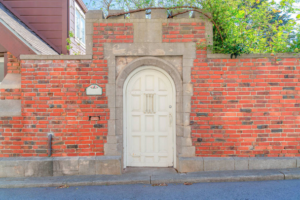 Porte cintrée en bois blanc avec murs en briques à San Francisco, Californie. Entrée d'une résidence avec des murs en béton contre le bâtiment et des arbres en arrière-plan. - Photo, image