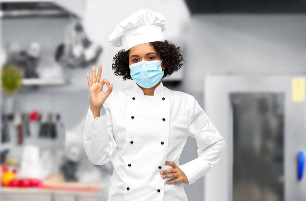female chef in medical mask and toque showing ok - Фото, зображення