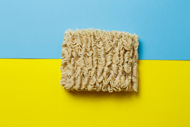 raw instant noodles on a blue and yellow background. - 写真・画像