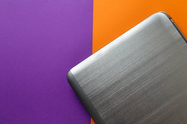 el portátil se encuentra sobre un fondo multicolor. fondo tendencia naranja y púrpura. - Foto, Imagen