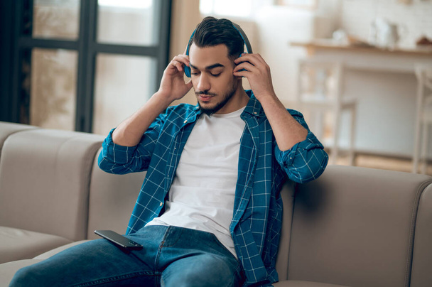 Young man in a blue tshirt listening to music and feeling good - Photo, image