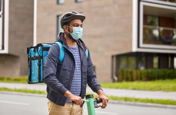 delivery man in mask with smatphone riding scooter - 写真・画像