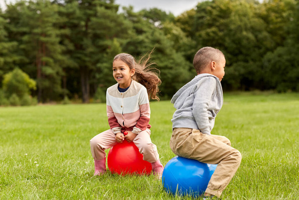 happy children bouncing on hopper balls at park - Foto, Bild