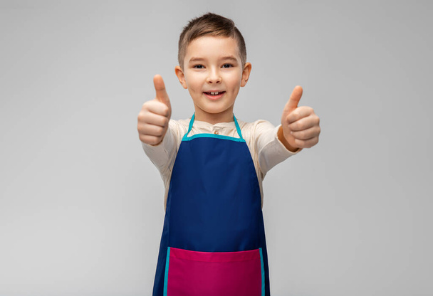smiling little boy in apron showing thumbs up - Φωτογραφία, εικόνα