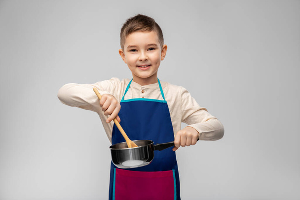 little boy in apron with saucepan cooking food - Foto, Bild