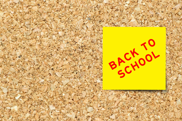 Yellow note paper with word back to school on cork board background with copy space - Foto, imagen
